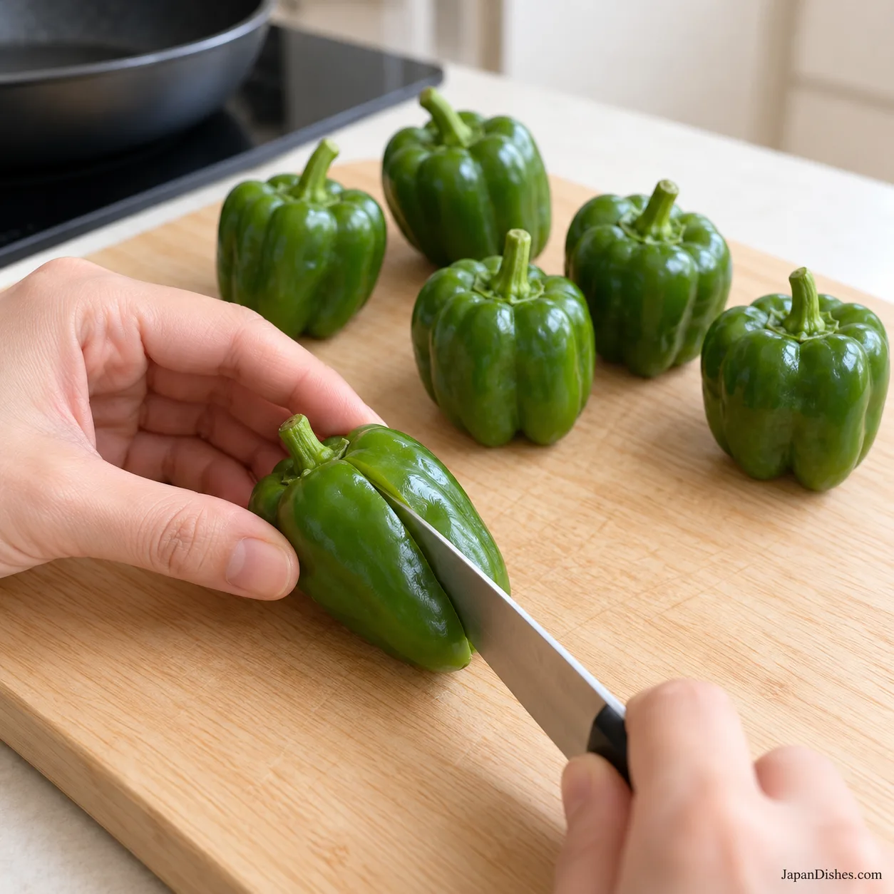 A knife making a single slit in one whole Japanese green pepper