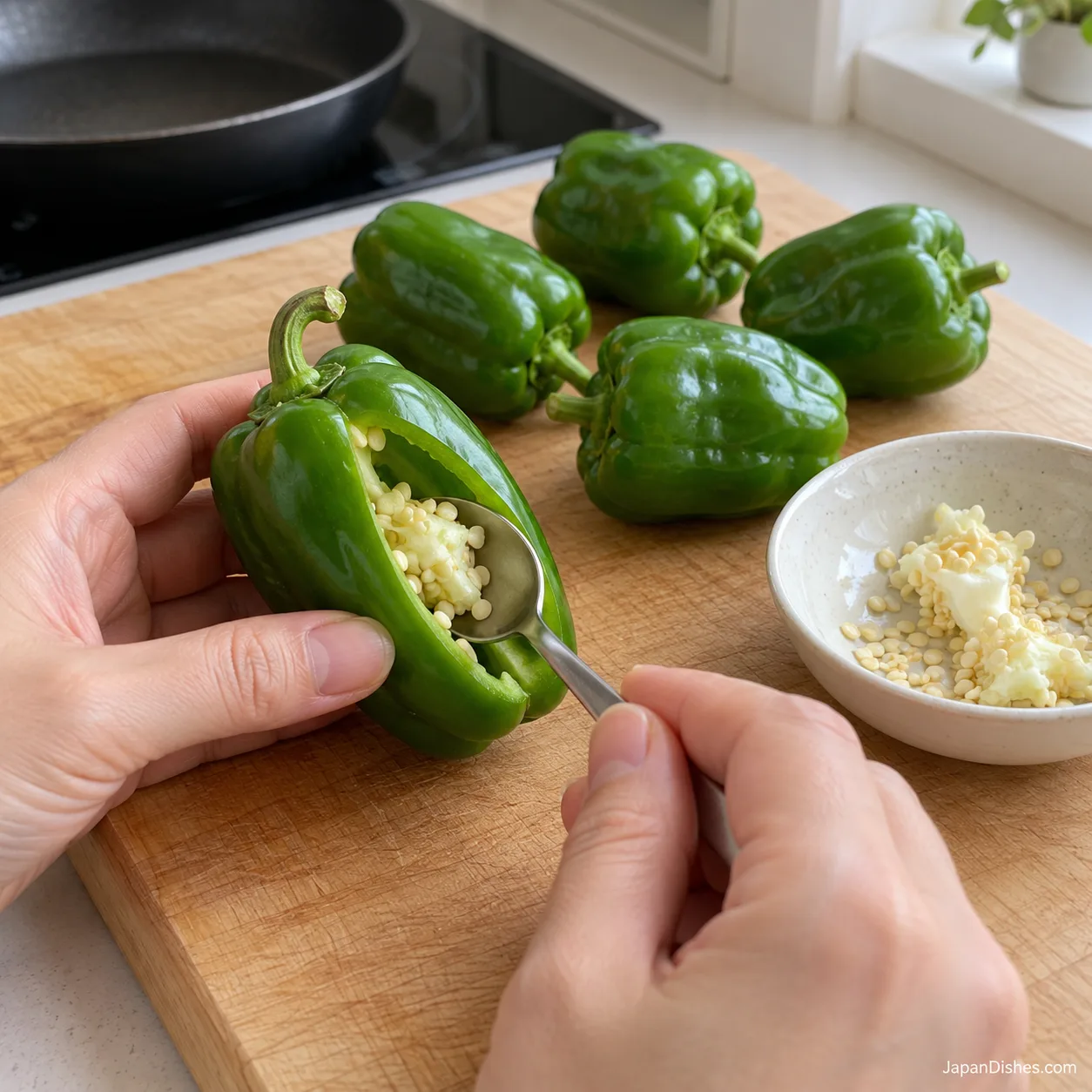 A teaspoon removing the seed core through a slit in a whole pepper