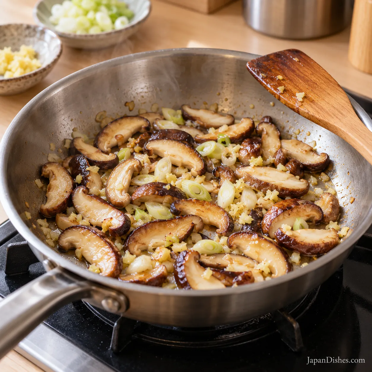 Sliced shiitake mushrooms sautéing with garlic, ginger and scallion whites in a skillet